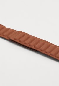 Brown leather strap featuring a series of padded sections, with a smooth texture and a slightly glossy finish.