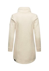 Dlhý rukáv, smotanový tunikový top s vysokým golierom, vyrobený z mäkkej tkaniny, s detailami švov a malou nášivkou pri spodnom leme.