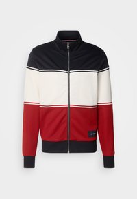 Giacca da uomo con zip e collo alto. Presenta righe orizzontali in blu navy, bianco e rosso. Realizzata in tessuto morbido con polsini a costine.