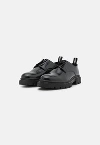 Black leather shoes with a smooth finish, rounded toe, lace-up design, and chunky rubber sole; includes pull tab on the heel.