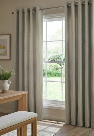 Tende grigio chiaro sono appese accanto a una grande finestra che mostra un giardino verde, con un tavolo in legno, una panca e un vaso con piante verdi all'interno.