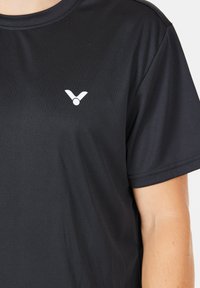 Svart kortärmad t-shirt i ett mjukt och lätt tyg. Har en liten vit logotyp nära bröstet och en avslappnad passform.