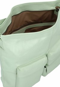 Mint green leather handbag with a smooth texture, featuring a zippered closure, inside pockets, and two front pockets.