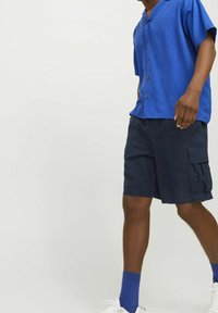 Camicetta azzurra a maniche corte con bottoni abbinata a pantaloni cargo blu navy. Presenta una vestibilità comoda e un tessuto testurizzato, adatta per un abbigliamento casual.