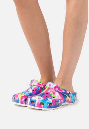 Sabots colorés avec un motif abstrait vibrant en rose, bleu et vert. Fabriqués en matériau léger avec des trous de ventilation et une sangle à l'arrière.