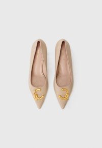 Ballerine beige a punta, realizzate in pelle liscia, con un dettaglio decorativo in hardware dorato sulla punta e un design semplice e minimalista.