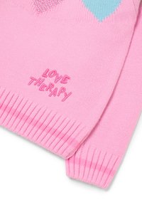 Roze gebreide trui met een hartontwerp in lichtblauw en strassversieringen. Tekst "LOVE THERAPY" geborduurd in roze.