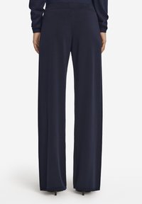 Marina vida braller i mjukt, elastiskt tyg med en slät textur. Har en dold midja och faller till golvet.