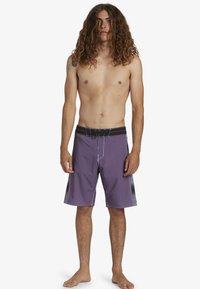 Fioletowe szorty plażowe z białymi szwami, czarnym pasem i bocznymi akcentami. Zaprojektowane z myślą o aktywnościach wodnych, charakteryzujące się luźnym krojem.