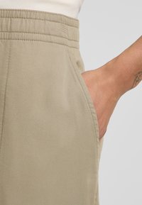 Beige broek met een soepele textuur en een gestikt elastische tailleband, met zijzakken en een op maat gemaakte pasvorm.