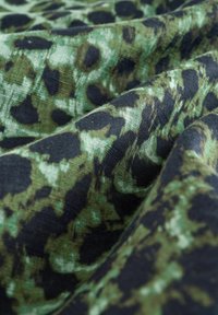 Groen en zwart stof met een luipaardprintpatroon, voorzien van een zachte, gestructureerde oppervlakte en een vloeiende uitstraling.