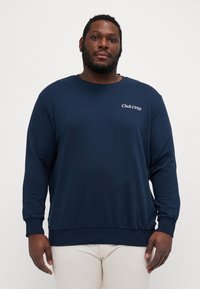 Marineblaues Sweatshirt aus Baumwolle mit langen Ärmeln. Mit weißem Text "Club1990" auf der Brust sowie gerippten Bündchen und Saum.