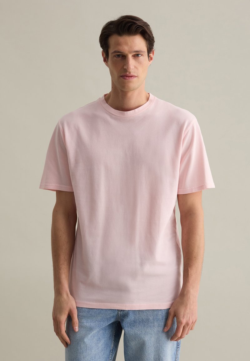 T-shirt rose clair à manches courtes et col rond, fabriqué en coton doux, avec une coupe décontractée et un design minimaliste.