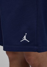 Marine sports shorts i et blødt materiale med et hvidt broderet Jumpman-logo på den nederste side. Har en lige kant og en subtil tekstur.
