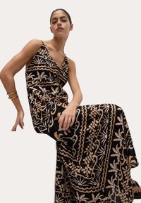 Abito lungo nero con motivi floreali e a onde beige. Presenta una profonda scollatura a V e spalline sottili, in tessuto fluido con una texture morbida.