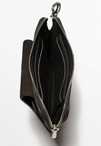 Portefeuille en daim noir avec une fermeture éclair, doté de compartiments intérieurs et d'un fermoir. L'intérieur présente une texture en cuir lisse et des coutures contrastées.