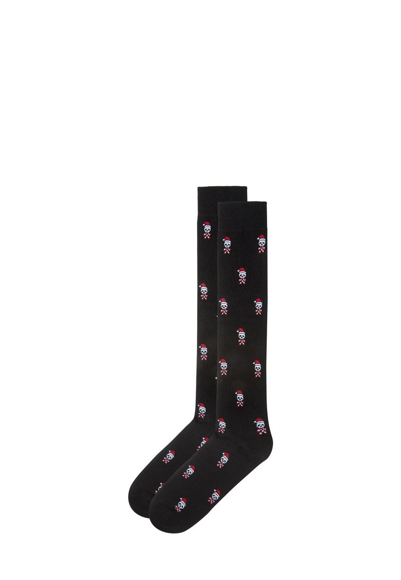 Black knee-high socks with repeated white skull and red Santa hat design. Smooth texture, elastic top, suitable for casual wear.
