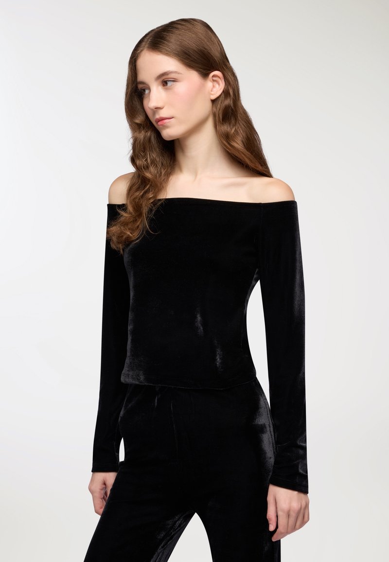Top in velluto nero off-the-shoulder con maniche lunghe, caratterizzato da una texture liscia e elegante e una silhouette aderente.