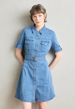 Denim shirt dress in light blue, features a collared neck, short sleeves with rolled cuffs, two chest pockets, and a belted waist with a button placket.