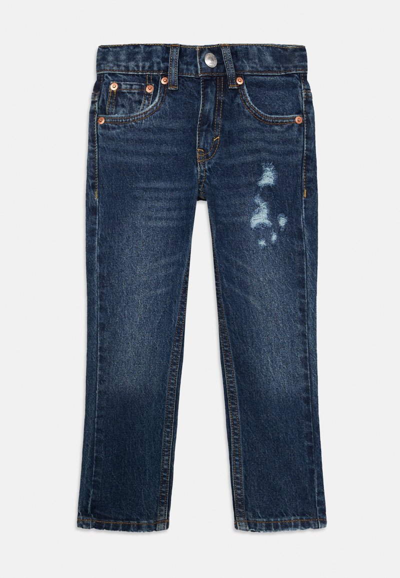 Jeans de ganga azul com corte reto, apresentando uma mancha desbotada na frente, rebites de cobre e costura amarela.