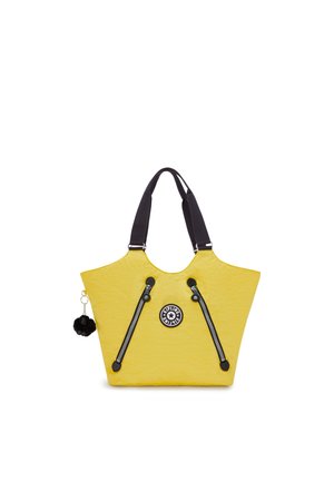 Yellow tote bag with black shoulder straps, featuring a textured finish, two zippers, and a circular logo on the front. Black pom-pom charm attached.