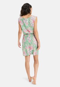 Vestido floral con fondo verde, que presenta patrones tropicales en rosa y blanco. Tela suave, mangas cortas y diseño de cintura elástica.