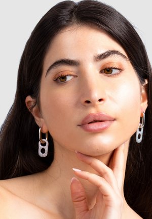 Silver chain link earrings with a textured surface, featuring a circular cutout and a smooth metal hook attachment.