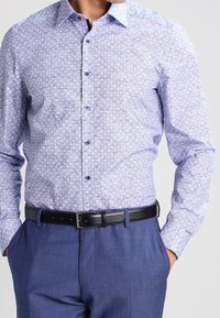 Light blue patterned dress shirt with a spread collar, button front, and long sleeves, paired with a black belt and blue dress trousers.