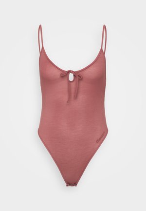 Ribbed one-piece swimsuit in dusty rose with adjustable straps, front tie detail, and high-cut legs. Subtle branding on the side.