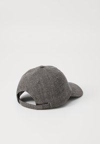 Gray cap made from textured fabric with a curved peak, adjustable strap at the back, and a logo accent near the strap.