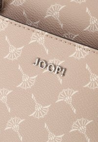 Portafoglio beige con motivo floreale in rilievo, caratterizzato da un logo metallico "JOOP!", superficie testurizzata e bordi lisci.