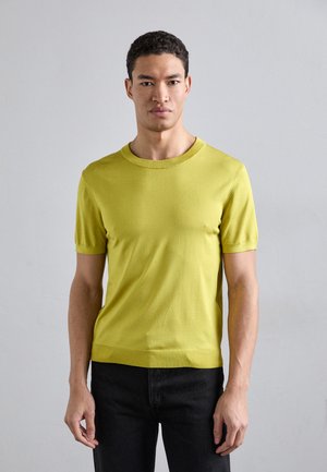Kortærmet t-shirt med rund hals i strålende gul strik. Blød tekstur med en tætsiddende form og minimale sømme. Bæres med mørke jeans.