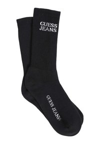 Čierne rebrované ponožky s bielym textom loga "GUESS JEANS" na manžete a časti chodidla. Vyrobené z hladkej, elastickej tkaniny.