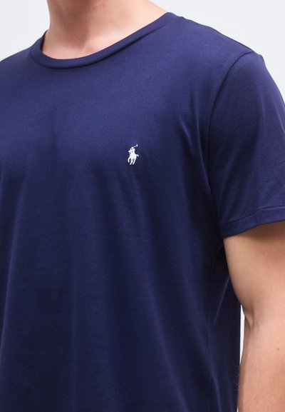 T-shirt de algodão azul marinho com decote redondo, mangas curtas e logótipo branco bordado no lado esquerdo do peito. Textura suave, corte clássico.