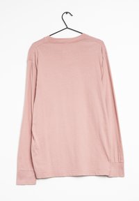 Long-sleeve shirt in soft pink fabric. Features a round neckline and stitched cuffs. Hangs on a black hook against a white background.