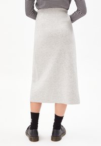 Gonna midi grigia in maglia con vita alta, texture liscia e una leggera forma a A, abbinata a calze nere e scarpe.