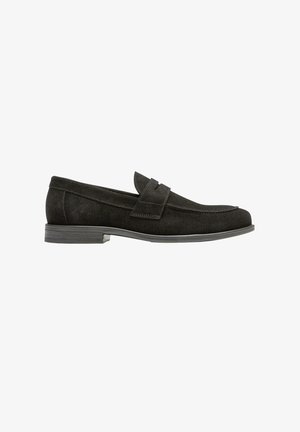 Mocassin homme en daim noir avec petit talon, bout rond et détail de bride sur le dessus, présenté de profil sur fond blanc.