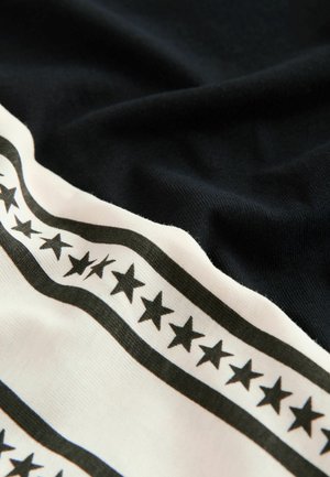 Svart tyg med en texturerad känsla, prytt med ett krämfärgat band dekorerat med ett upprepat svart stjärnmönster längs dess nedre kant.