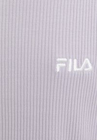 Tessuto ribbed di colore viola chiaro con logo ricamato "FILA" in bianco. La texture è liscia con righe verticali in tutto il tessuto.