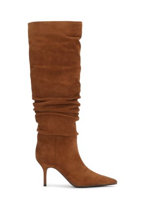 Botte haute en daim marron décontractée avec bout pointu et talon fin de hauteur moyenne sur fond blanc.
