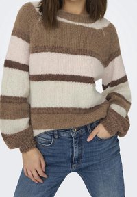 Brązowy i beżowy sweter w paski z dzianiny, okrągłym dekoltem i bufiastymi rękawami, zestawiony z niebieskimi dżinsami. Miękka faktura i przytulny design.