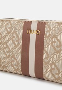 Portafoglio beige con motivo e texture liscia, caratterizzato da una striscia verticale marrone e logo in hardware dorato "LIU•JO." Chiusura a zip nella parte superiore.