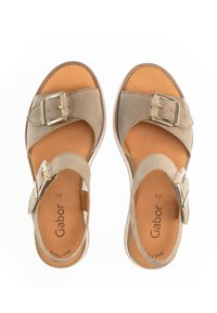 Beige suede sandals with two adjustable straps, gold hardware accents, and a cushioned tan insole. Flat sole for comfort.