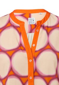 Knopfbluse aus leichtem Stoff; mit einem kreisförmigen rosa-orange Muster, hellorangefarbenem Kragen und pinken Knöpfen. Markenlabel sichtbar.