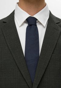 Menns dressjakke i mørkegrå med et fint rutemønster, kombinert med en hvit skjorte og et ensfarget marineblått slips.