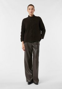 Dark brown knitted sweater with a high collar and cable knit pattern, paired with high-waisted, wide-leg brown leather pants.