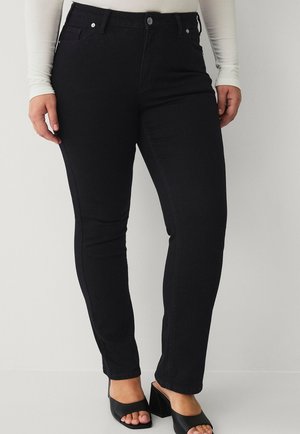 I jeans skinny in denim nero presentano un classico design a cinque tasche, chiusura con bottone e una trama liscia. Abbinati a sandali con tacco a blocco open-toe.