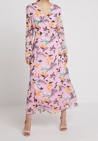 Abito avvolgente a maniche lunghe con motivo floreale su sfondo rosa, con elementi arancioni, gialli e verdi; orlo fluido e tessuto trasparente.