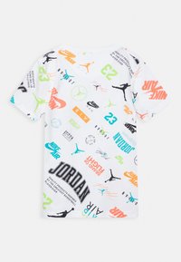 Camiseta de manga corta blanca con varios logotipos y gráficos en naranja, verde, negro y azul, incluyendo "JORDAN" y siluetas de baloncesto.