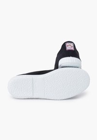 Czarna płócienna tenisówka z białą gumową podeszwą. Posiada teksturowaną spodnią część i metkę z rysunkową małpką z tyłu. Wyprodukowano w Japonii.